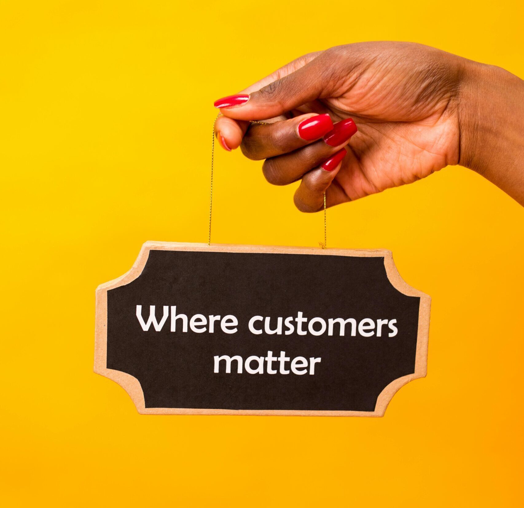 Hand holding a sign with 'Where customers matter' on a vibrant yellow backdrop.